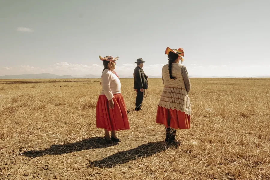 Tres figuras humanas de pie, separadas entre sí por varios metros, observando la inmensidad de una llanura desolada y seca hasta donde alcanza la vista.
