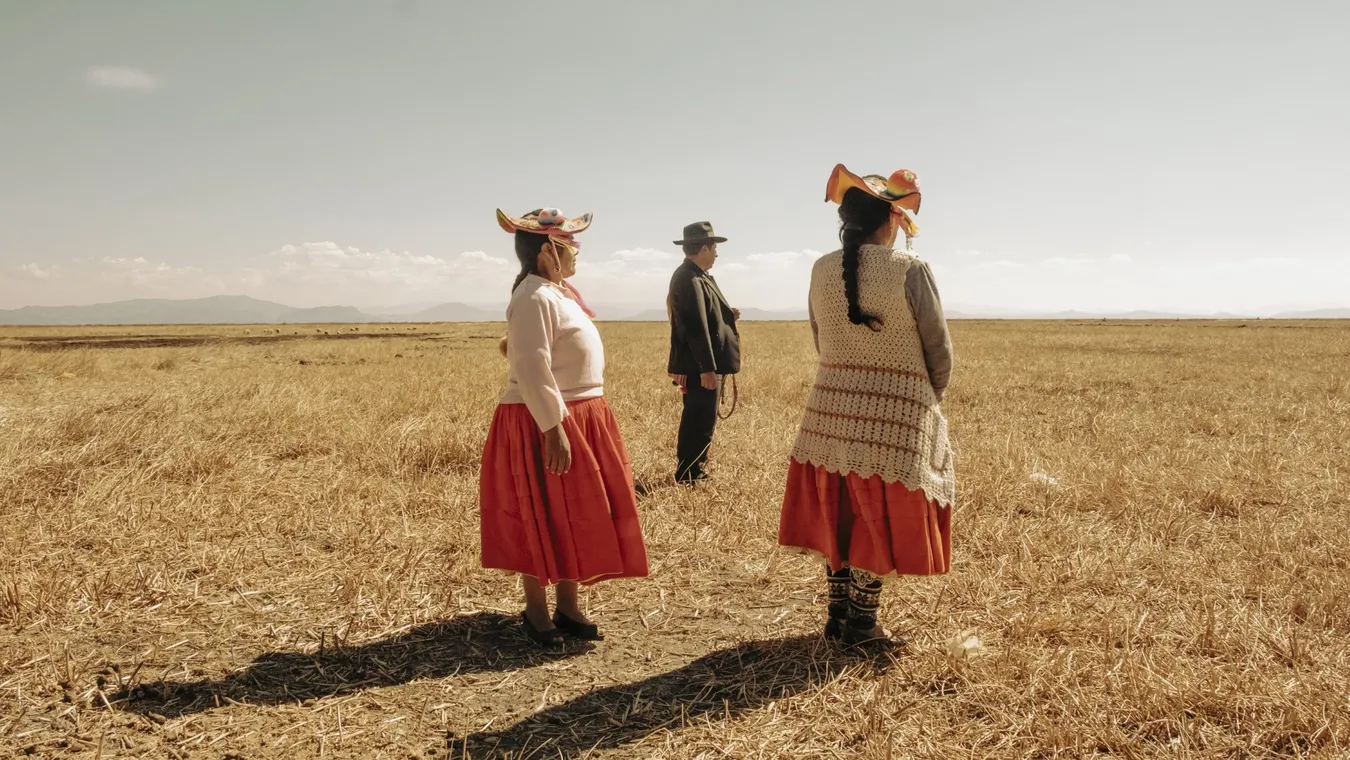 Tres figuras humanas de pie, separadas entre sí por varios metros, observando la inmensidad de una llanura desolada y seca hasta donde alcanza la vista.