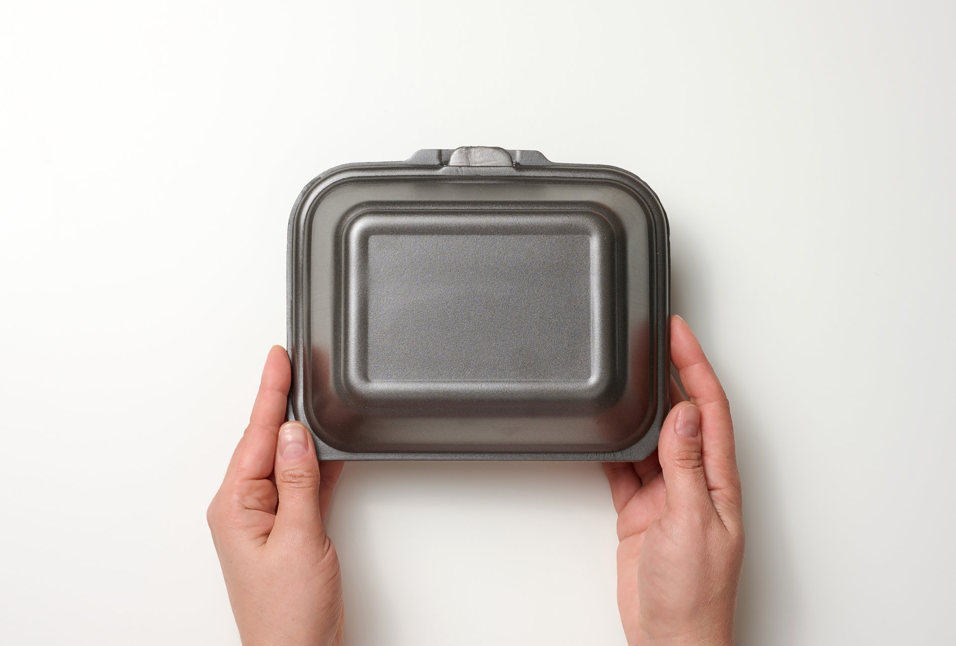 female-hand-holds-disposable-food-container-gray-box-of-polystyrene-on-white-background
