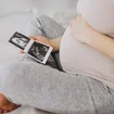 pregnant-woman-with-ultrasound-photo-sitting-on-bed