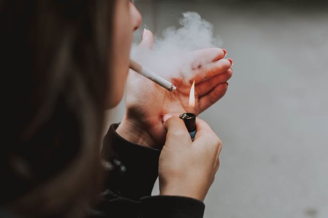 selective-closeup-shot-female-lighting-up-cigarette-with-lighter