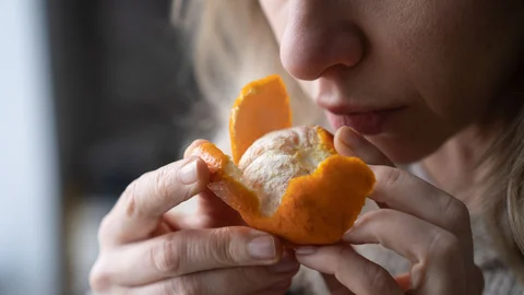 sick-woman-trying-to-sense-smell-of-fresh-tangerine-orange-has-symptoms-of-covid-19-corona-virus.jpg