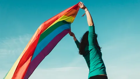 unrecognizable_young_girl_raising_gay_pride_flag_above_her_head.jpg