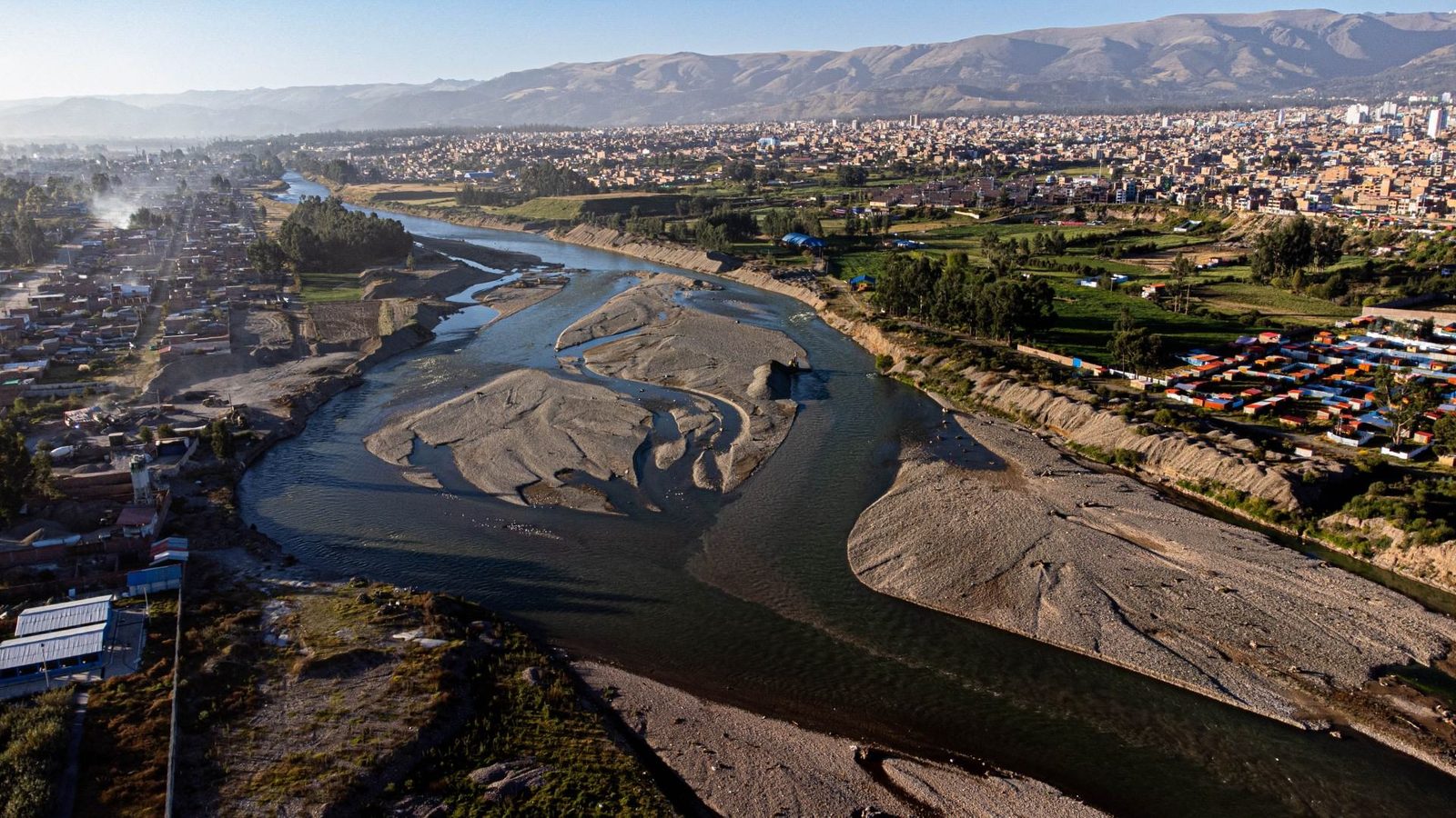 Vista aérea de un río con bancos de arena que atraviesa el valle junto a una ciudad